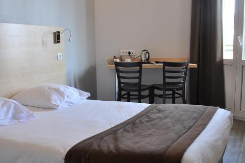 - une chambre avec un lit, une table et des chaises dans l'établissement Hotel Foch Nancy Gare, à Nancy