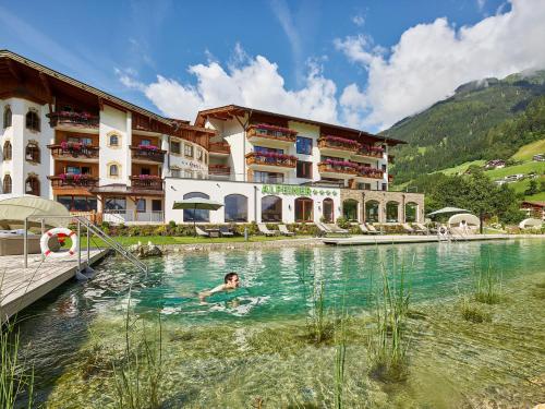 uma pessoa a nadar numa piscina em frente a um hotel em Alpeiner - Nature Resort Tirol em Neustift im Stubaital