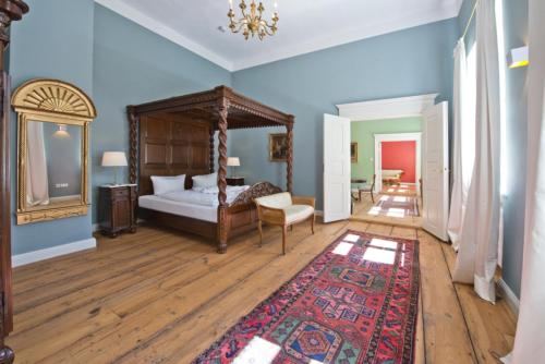 een slaapkamer met een hemelbed en een tapijt bij Schloss Retzow Apartments in Retzow