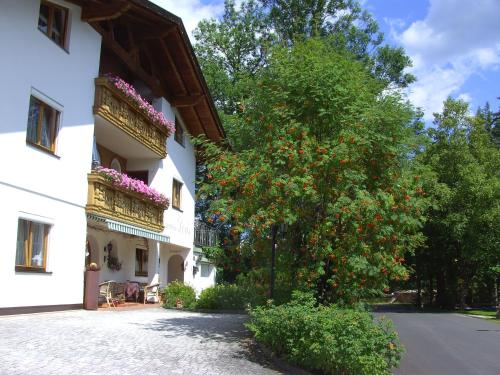 ein weißes Gebäude mit Blumen auf den Balkonen und einem Baum in der Unterkunft Landhaus Doris in Leutasch