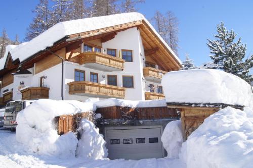 ein schneebedecktes Haus mit Garage in der Unterkunft Ferienwohnungen am Lärchenweg in Sexten