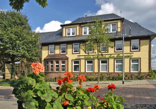 um edifício amarelo com flores vermelhas em frente em Pension Haus Saarland em Oberhof