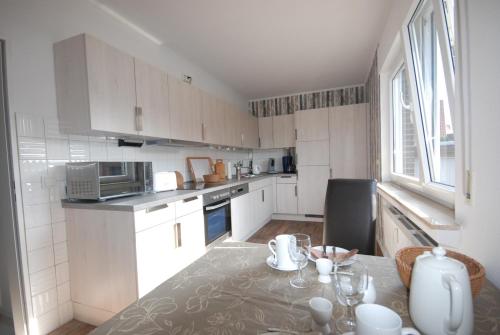 a kitchen with white cabinets and a table with glasses on it at Gästehaus Spengler in Celle