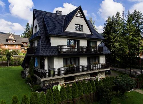 a house with a black roof on a green yard at Willa Pod Lasem in Kościelisko