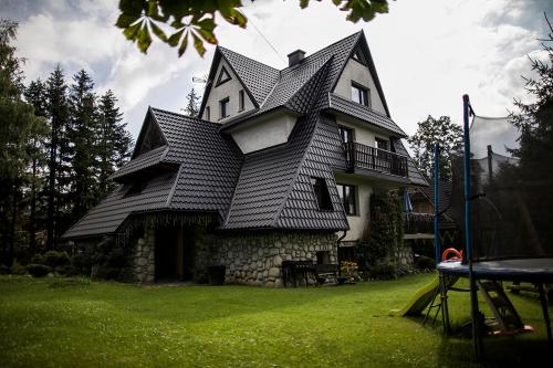 a house with a gambrel roof on top of a yard at Willa Pod Lasem in Kościelisko