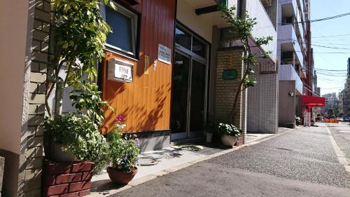 ein Gebäude mit Topfpflanzen an der Straßenseite in der Unterkunft Kasuga Ryokan in Hiroshima