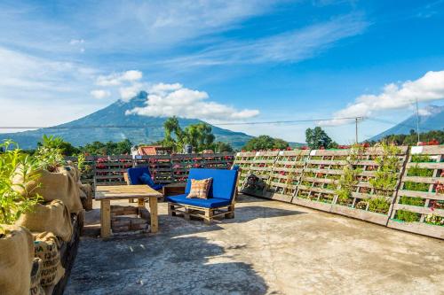 un patio avec deux chaises bleues et une table sur le toit dans l'établissement The Purpose Hostel, à Antigua Guatemala