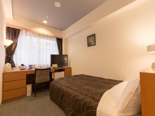 una camera d'albergo con letto e scrivania di Osaka Moriguchi Plaza Hotel ad Osaka