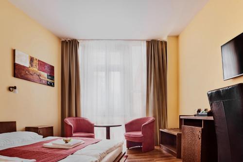 een hotelkamer met een bed en twee stoelen en een raam bij Hotel Banderium in Komárno