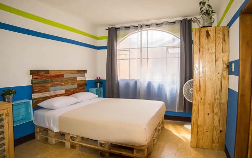 - une chambre avec un lit aux rayures bleues et vertes dans l'établissement The Purpose Hostel, à Antigua Guatemala