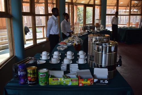 twee mannen voor een lange tafel met eten bij Roika Tarangire Tented Lodge in Kwa Kuchinia