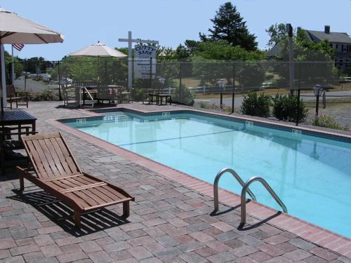 a swimming pool with a wooden bench and a chair at The Cutty Sark in Dennis Port