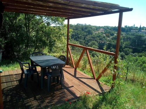 eine Holzterrasse mit einem Tisch und Stühlen darauf in der Unterkunft Le Chalet du Parc in Annonay