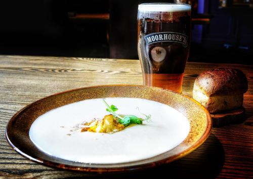 een bord eten op een tafel met een biertje bij Shibden Mill Inn in Halifax