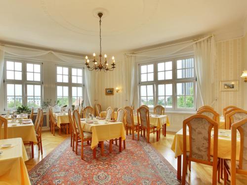 ein Esszimmer mit Tischen, Stühlen und einem Kronleuchter in der Unterkunft Hotel Bellmoor im Dammtorpalais in Hamburg