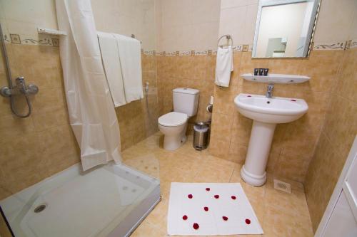 La salle de bains est pourvue d'un lavabo, de toilettes et d'une douche. dans l'établissement Mutrah Hotel, à Mascate