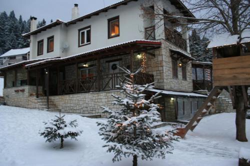 un albero di Natale coperto di neve davanti a una casa di Villa Filokosta a Pertouli (Pertoúlion)