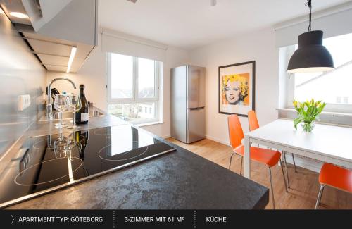 cocina con encimera y mesa con sillas de color naranja en HEJ Apartments Bayreuth, en Bayreuth