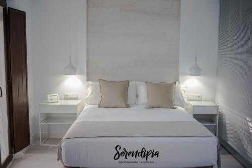 una camera da letto con un grande letto bianco con due tavoli di Serendipia San Justo a Cáceres