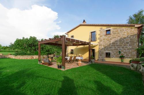 einen Hinterhof mit einer hölzernen Pergola und einem Haus in der Unterkunft FicOlivo in Pitigliano