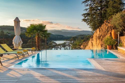 una piscina con sedie, ombrellone e lago di Auberge Du Lac a Saint-Marcel-lès-Annonay