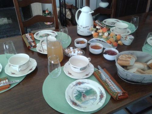 a wooden table topped with plates and cups of food at LES JARDINS DE LA GRANGE in Rezonville