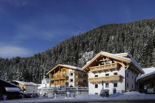 a large building in the snow with a mountain at Gasthof Burkert in Oetz