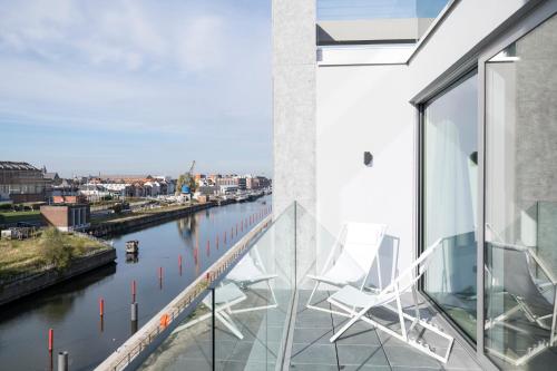 two white chairs sitting on a balcony overlooking a river at Skyline Flats Gent in Ghent