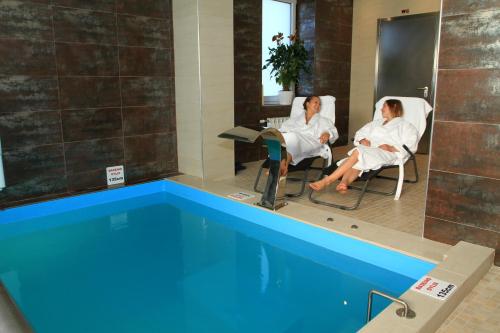 2 femmes assises sur des chaises à côté d'une piscine dans l'établissement Grafo Zubovo Hotel & SPA, à Bubiai