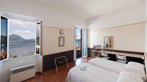 a living room with a bed and a desk with a computer at Hotel Eden in Baveno