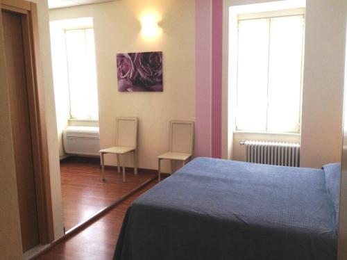 a bedroom with two chairs and a bed and two windows at Hotel Eden in Baveno