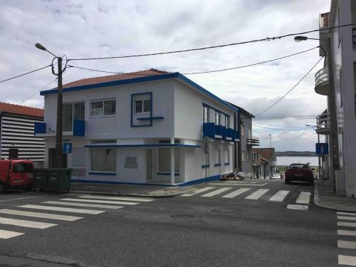 een wit gebouw met blauwe accenten in een straat bij SEA RIA - A casa dos Maria in Costa Nova