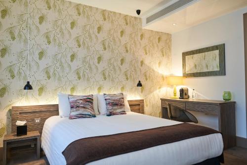 1 dormitorio con cama y pared con papel pintado en Hotel Bosco, en Kingston upon Thames