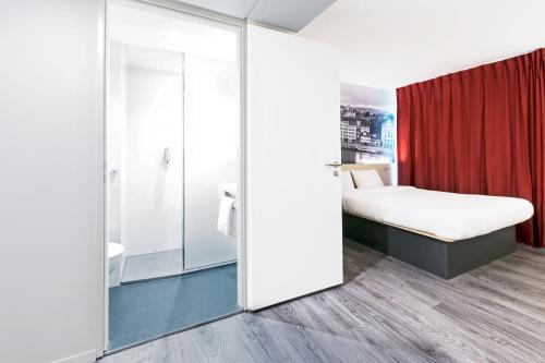 een slaapkamer met een bed en een glazen deur met een douche bij B&B HOTEL Zürich Airport in Rümlang