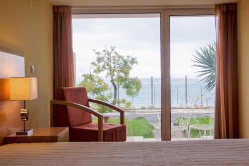 Habitación de hotel con cama, silla y ventana en INATEL Oeiras, en Oeiras