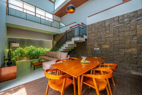 a dining room with a wooden table and chairs at Agranusa Signature Villa Nusa Dua in Nusa Dua