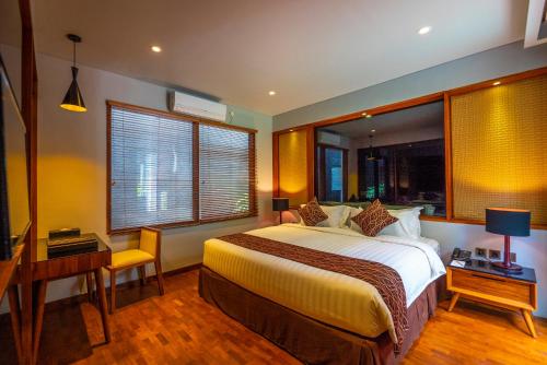 a bedroom with a bed and a desk and windows at Agranusa Signature Villa Nusa Dua in Nusa Dua