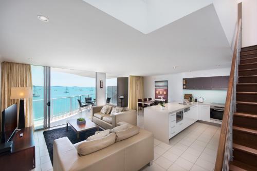 a living room with a couch and a kitchen at at Marina Shores in Airlie Beach