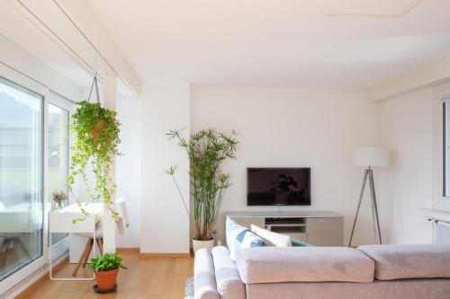 a white living room with a couch and some plants at Modern & Central Apartments in Luzern