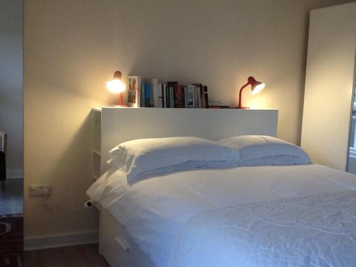 a bedroom with a white bed with two pillows at Highfield Cottage in Kirknewton