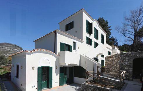 een groot wit gebouw met groene luiken erop bij Il Ducato Di Ravello in Ravello