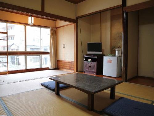 ein Wohnzimmer mit einem Tisch und einem Kühlschrank in der Unterkunft Kimatsu Ryokan in Hiroshima