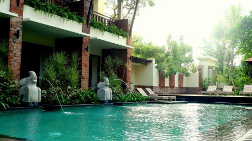 una piscina frente a un edificio con estatuas en el agua en Arena Living, en Sanur