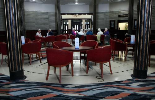 eine Gruppe von Personen, die an Tischen und Stühlen in einem Zimmer sitzen in der Unterkunft Royal Maritime Hotel in Portsmouth