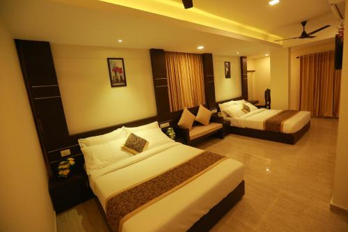 ein Hotelzimmer mit 2 Betten und einem Sofa in der Unterkunft The Crescent Suites in Ernakulam