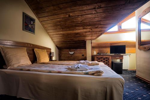 ein Schlafzimmer mit einem großen Bett und einer Holzdecke in der Unterkunft Kap House Family Hotel in Bansko