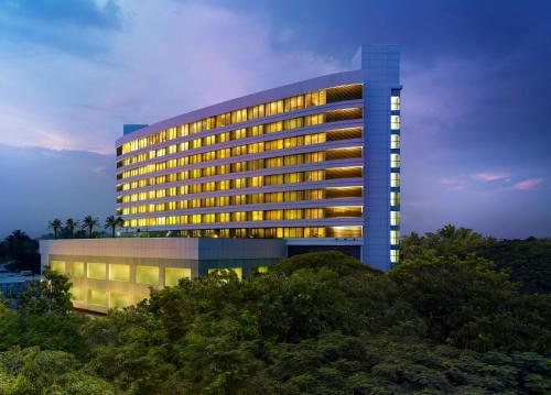 a lit up building with trees in front of it at Vivanta Coimbatore in Coimbatore