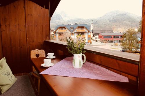 a table with a vase of flowers on a table with a window at Ferienwohnung Seilbahn in Sankt Gilgen