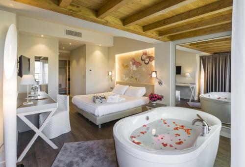 ein Badezimmer mit einer Badewanne und ein Schlafzimmer mit einem Bett in der Unterkunft Hotel Resort & Spa Miramonti in Rota d'Imagna