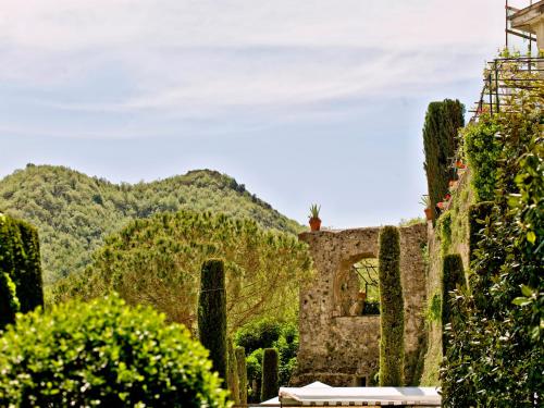 un antico edificio in pietra con alberi e montagne sullo sfondo di Hotel Scapolatiello a Cava deʼ Tirreni